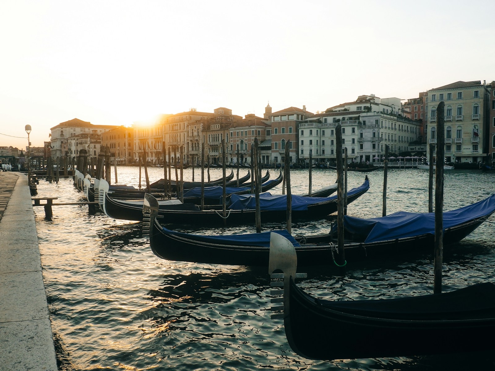 Gondolas docked along a canal in venice at sunset